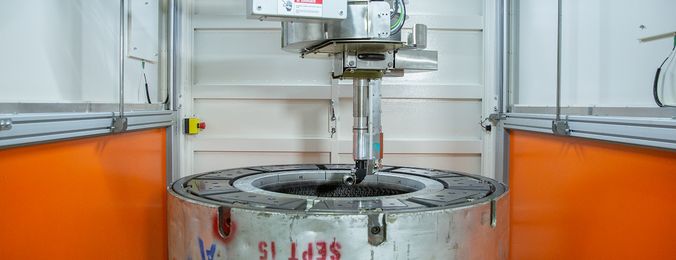 Das Bild zeigt das Innere der STMCS, in welcher eine Reifenform unter einem Laserprozesskopf positioniert ist.