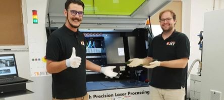4JET Mitarbeiter stehen im neuen MicroFab JobShop vor einer der Lasermaschinen.