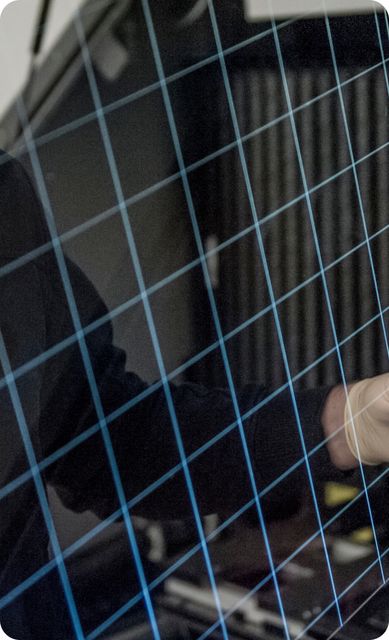 Ein Mitarbeiter hält ein strukturiertes Glassubstrat in den Händen.