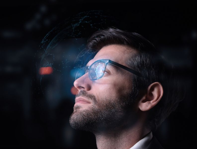 Ein Mann hat eine VR-Brille auf. In den Gläsern der Brille werden digitale Grafiken angezeigt.