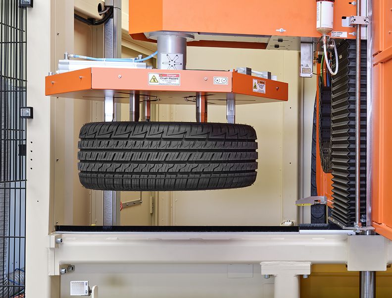 Der Greifarm des Tire-Cleaning-Systems transportiert den nächsten Reifen zur Bearbeitung in die Maschine. 