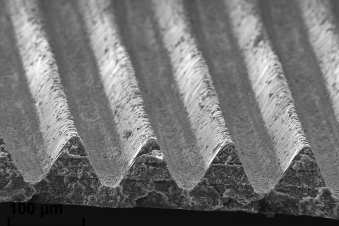 Mikroskopaufnahmen der erzeugten Strukturen. Man sieht gleichmäßige, parallele Vertiefungen im Substrat.