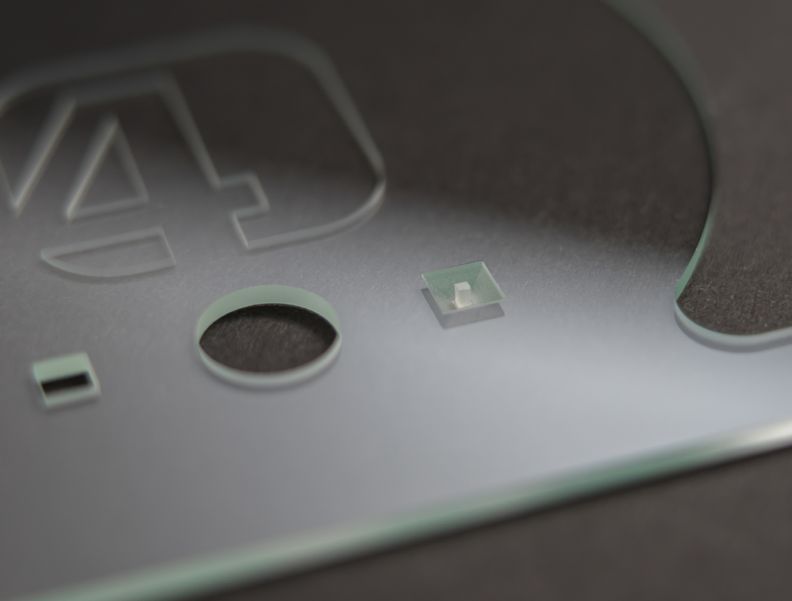 Auf dem Foto ist eine Glasstück mit Bohrungen unterschiedlicher Form und Durchmessern zu sehen.