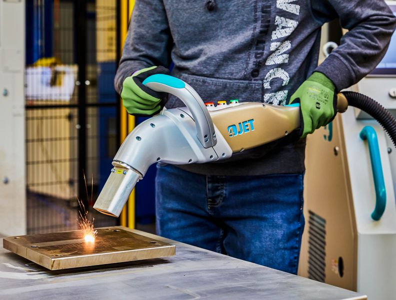 Ein Arbeiter reinigt eine metallische Oberfläche mit dem JETLASER.
