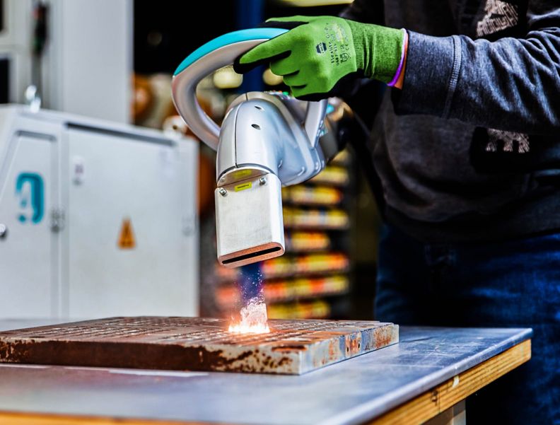 Ein Arbeiter trägt Sicherheitsausrüstung und reinigt ein mechanisches Bauteil.