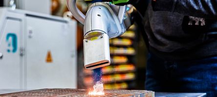 Ein Arbeiter trägt Sicherheitsausrüstung und reinigt ein mechanisches Bauteil.