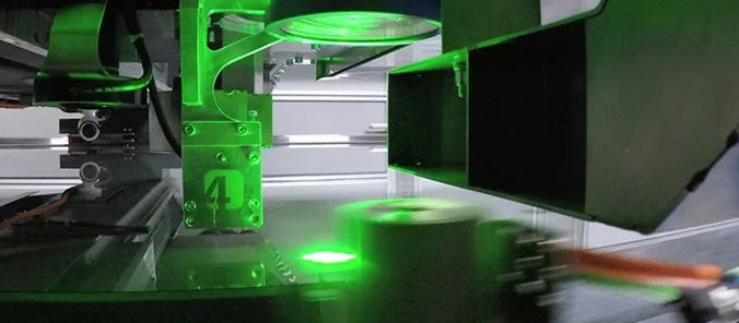 Ein grüner Laserstrahl bearbeitet ein gläsernes Substrat.