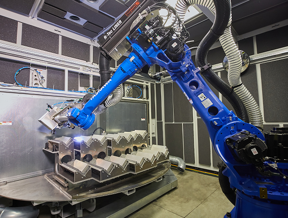 Ein Roboterarm mit einem Laser bearbeitet Metallkomponenten vollautomatisch. 