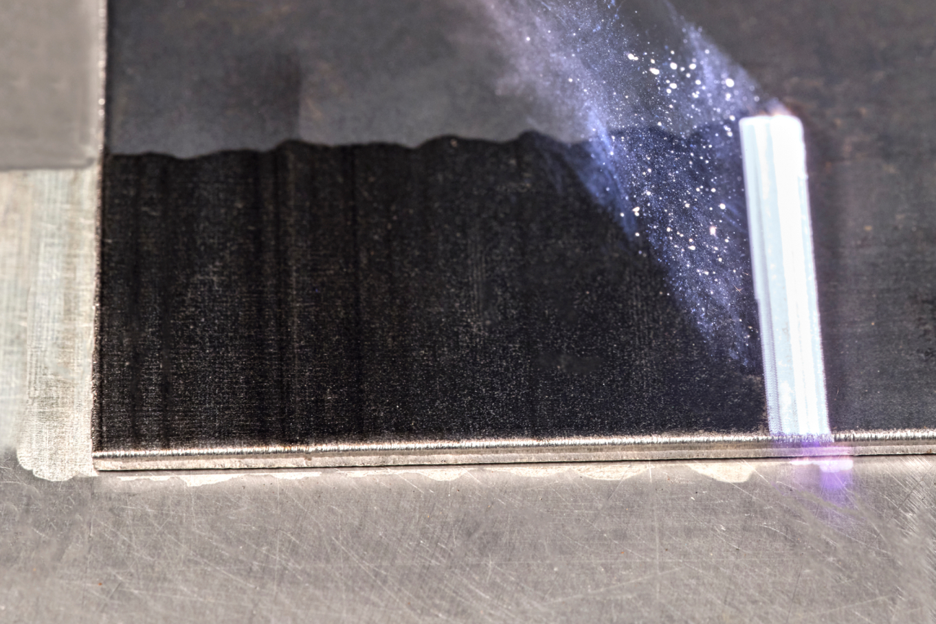 Auf einer metallischen Fläche wird eine Farbschicht entfernt.