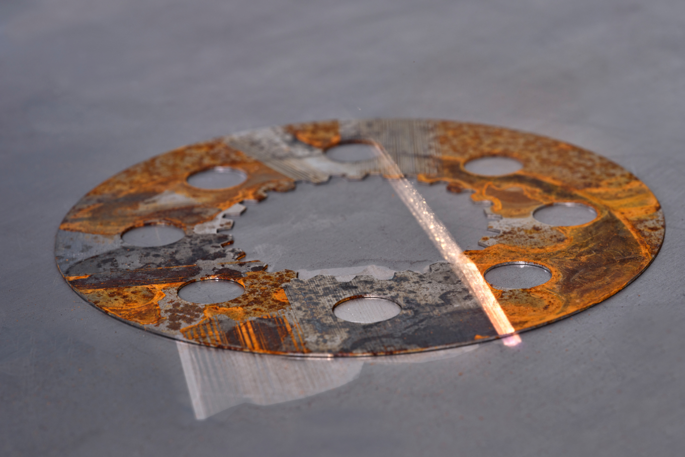 Per Laserstrahl wird ein Metallstück von Rost befreit.