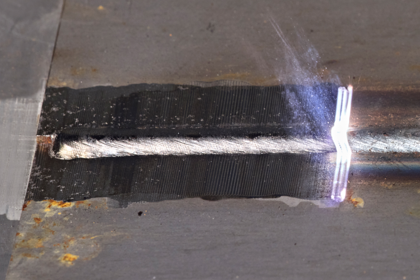 Eine Schweißnaht auf einer Metallfläche wird per Laser gereinigt.
