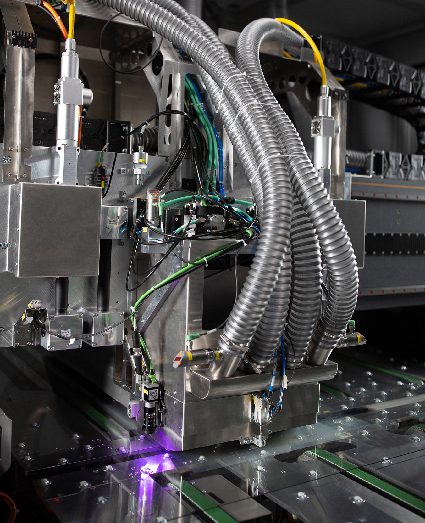 Prozesskopf einer Laserglasbearbeitungsanlage. Erkennbar sind zwei Faserlaser und vier Absaugschläuche.