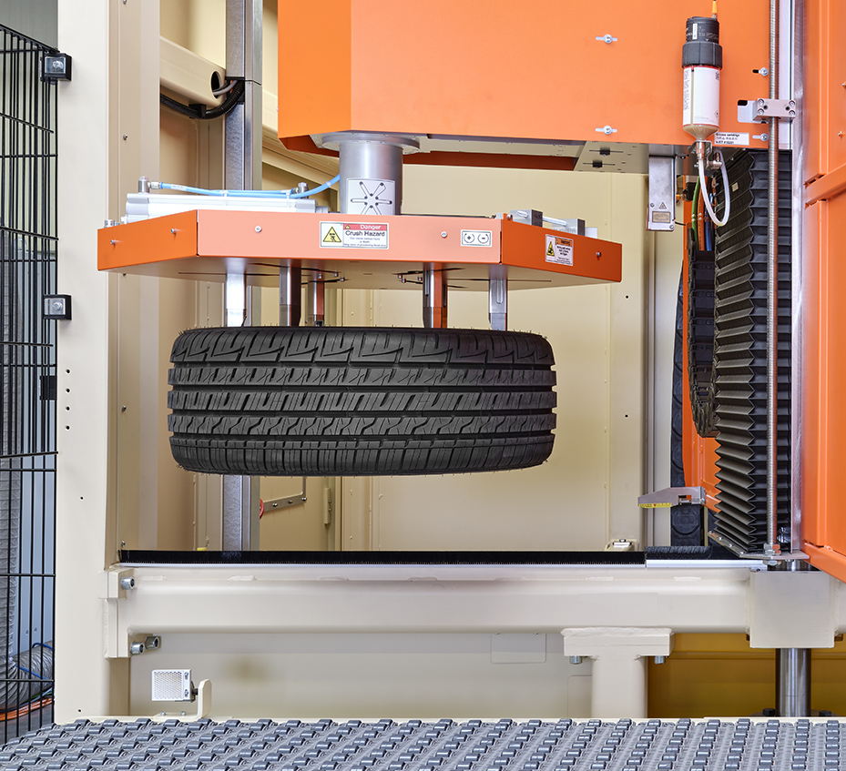 Der Greifarm des Tire-Cleaning-Systems transportiert den nächsten Reifen zur Bearbeitung in die Maschine. 