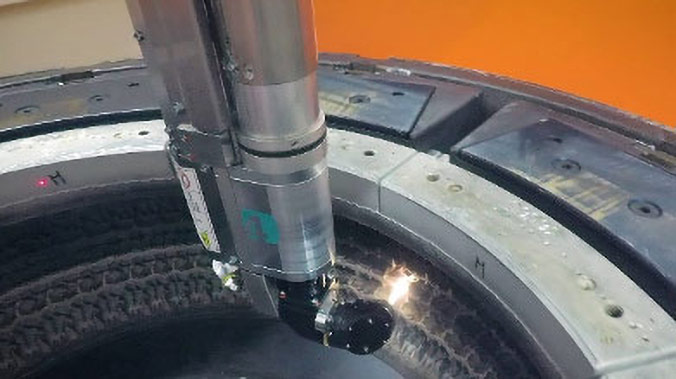 Ein Reinigungskopf entfernt mit einem hellen Laserstrahl Verunreinigungen auf der Reifenform.