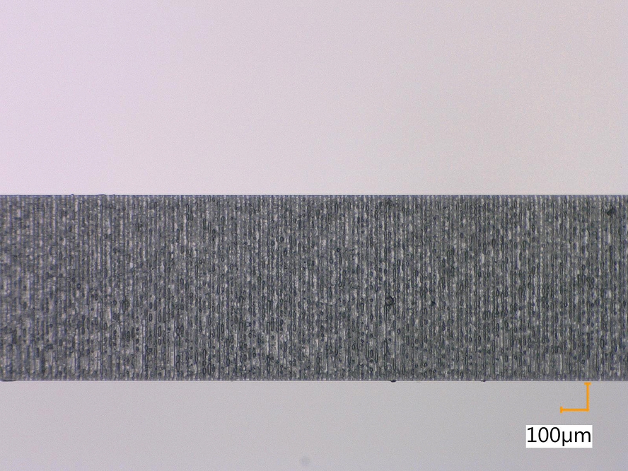 Die mikroskopische Aufnahme zeigt den Querschnitt einer Glaskante. Diese zeigt sich als einen grauen Balken mit exakt geschnittenen Rändern im Bild.