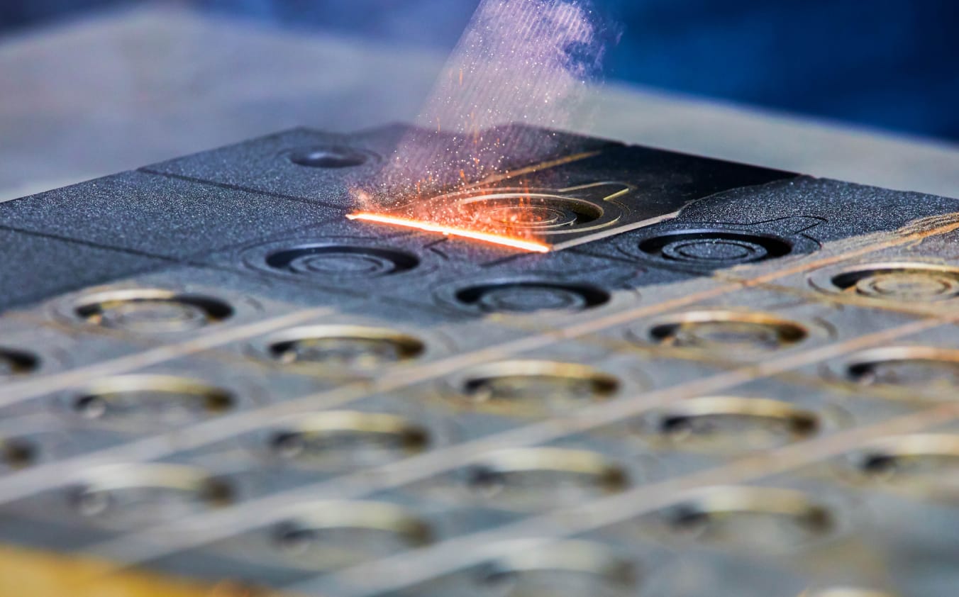 Laserstrahlen treffen auf eine verdreckte Metallform und hinterlassen eine saubere Oberfläche.