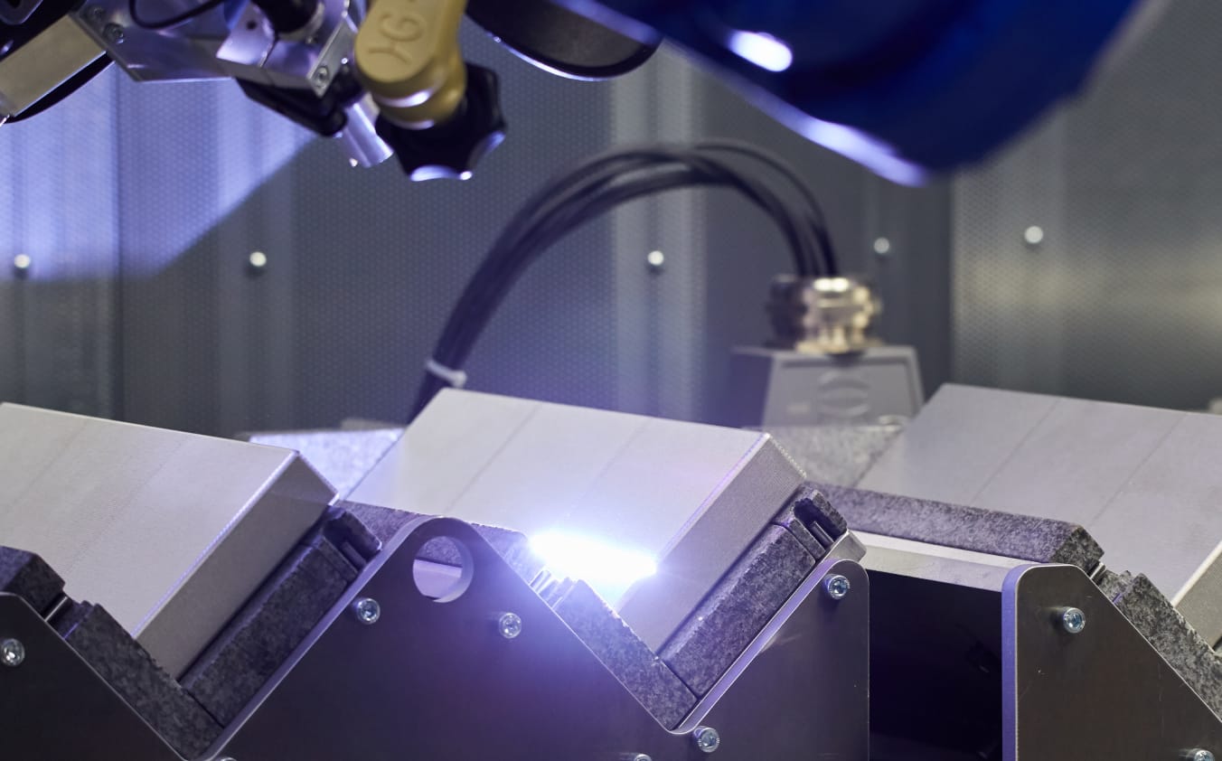 Metallische Bauteile werden mit einem hellen Laserstrahl gereinigt.