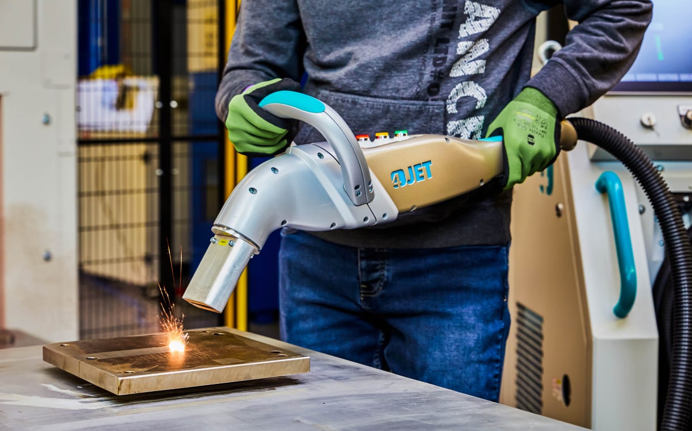 Ein Arbeiter reinigt ein mechanisches Bauteil.