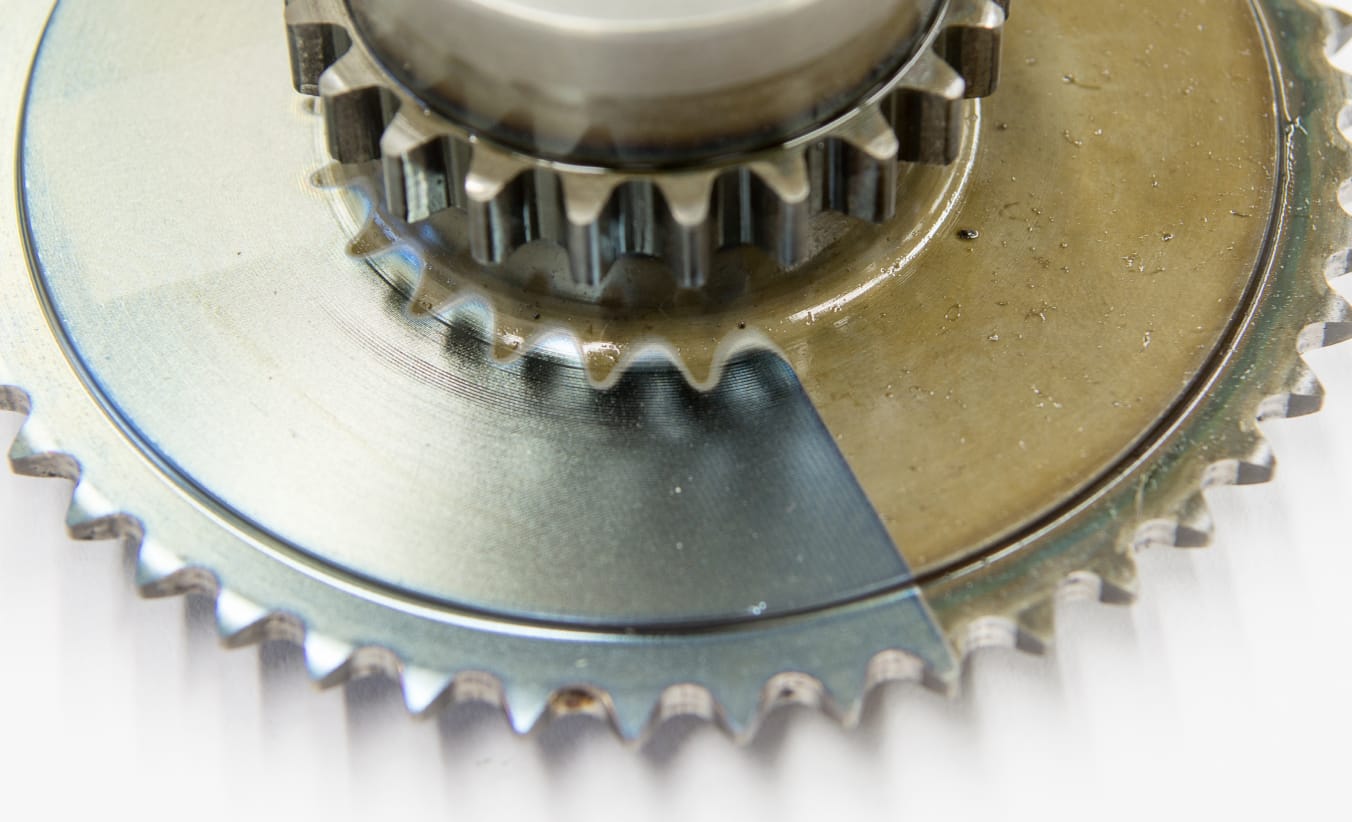 Ein Getriebe-Zahnrad ist zur Hälfte von einer Schicht Öl bedeckt. Die andere Hälfte wurde mit dem Laser gereinigt.  