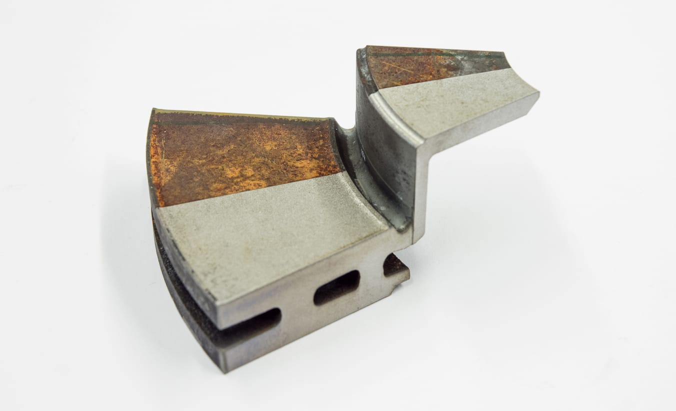 Die Hälfte eines Bremsscheibensegments wurde per Laser entrostet. Oben ist die Scheibe noch von einer Schicht Rost überzogen, unten ist die gereinigte, metallische Oberfläche zu sehen.