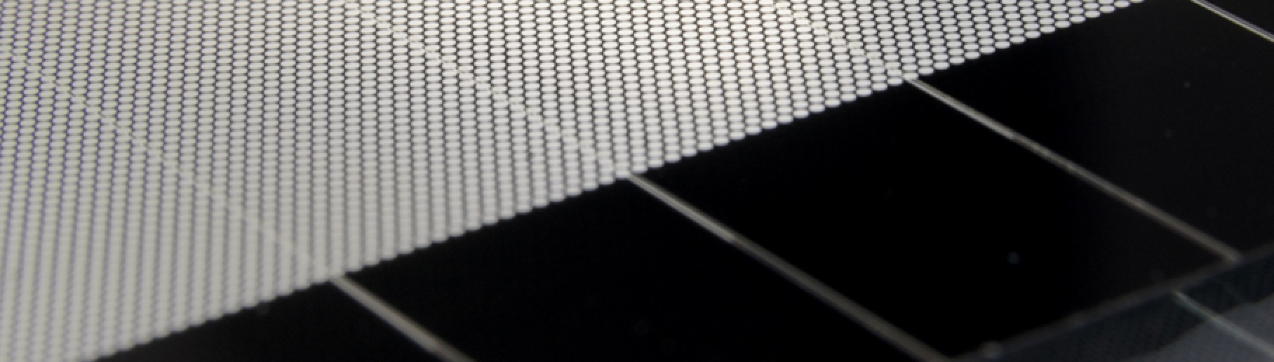 Die Darstellung zeigt eine dunkle Glasscheibe mit einer hohen Anzahl regelmäßig angeordneter heller Punkte.