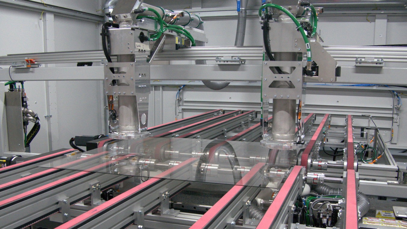 Das innere einer Laserentschichtungsanlage, in welcher durch das Glas hindurch eine funktionale Schicht am Glasrand abgetragen wird. 