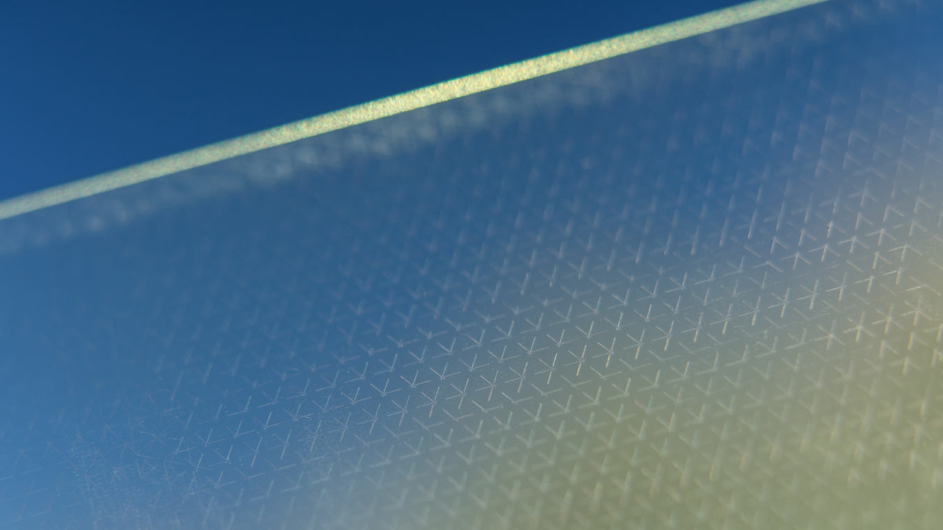 Eine funktionale Schicht auf einer Glasscheibe,z.B. eine Low-E-Beschichtung, wird mithilfe von Laserstrukturierung in einem spezifischen Muster abgetragen um die Funktionseigenschaften zu beeinflussen. Hierdurch wird zum Beispiel die Transmission spezifischer wellenlängen ermöglicht. 