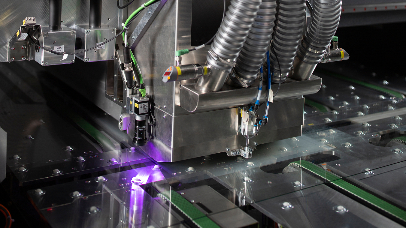 Prozesskopf einer Laserglasbearbeitungsanlage. Erkennbar sind zwei Faserlaser und vier Absaugschläuche.