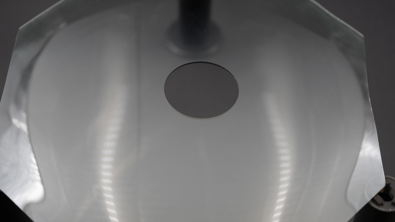 Image of a curved glass substrate with a round hole in the center.