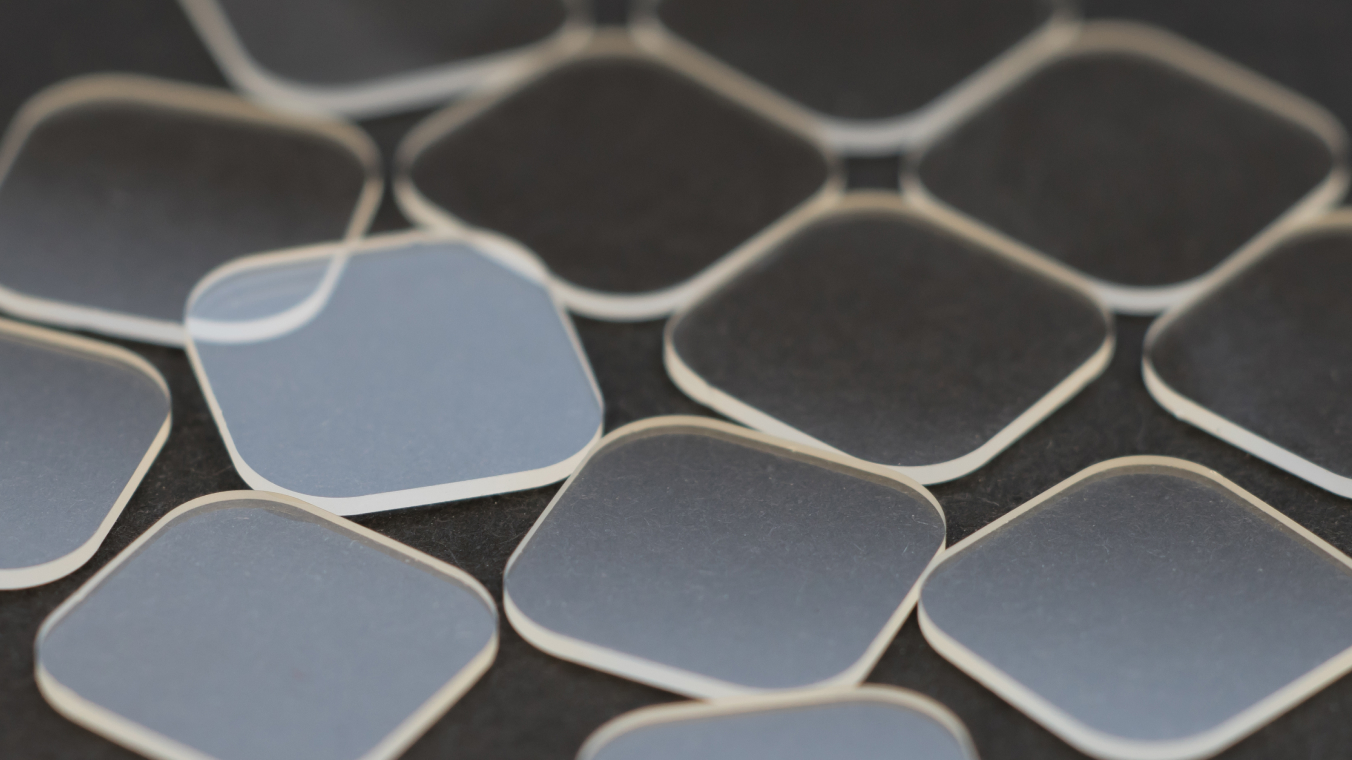 Mehrere lasergeschnittene quadratische Glasbauteile mit abgerundeten Ecken.