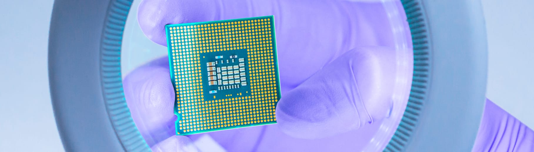 Eine Person hält einen Mikrochip unter eine Lupe.