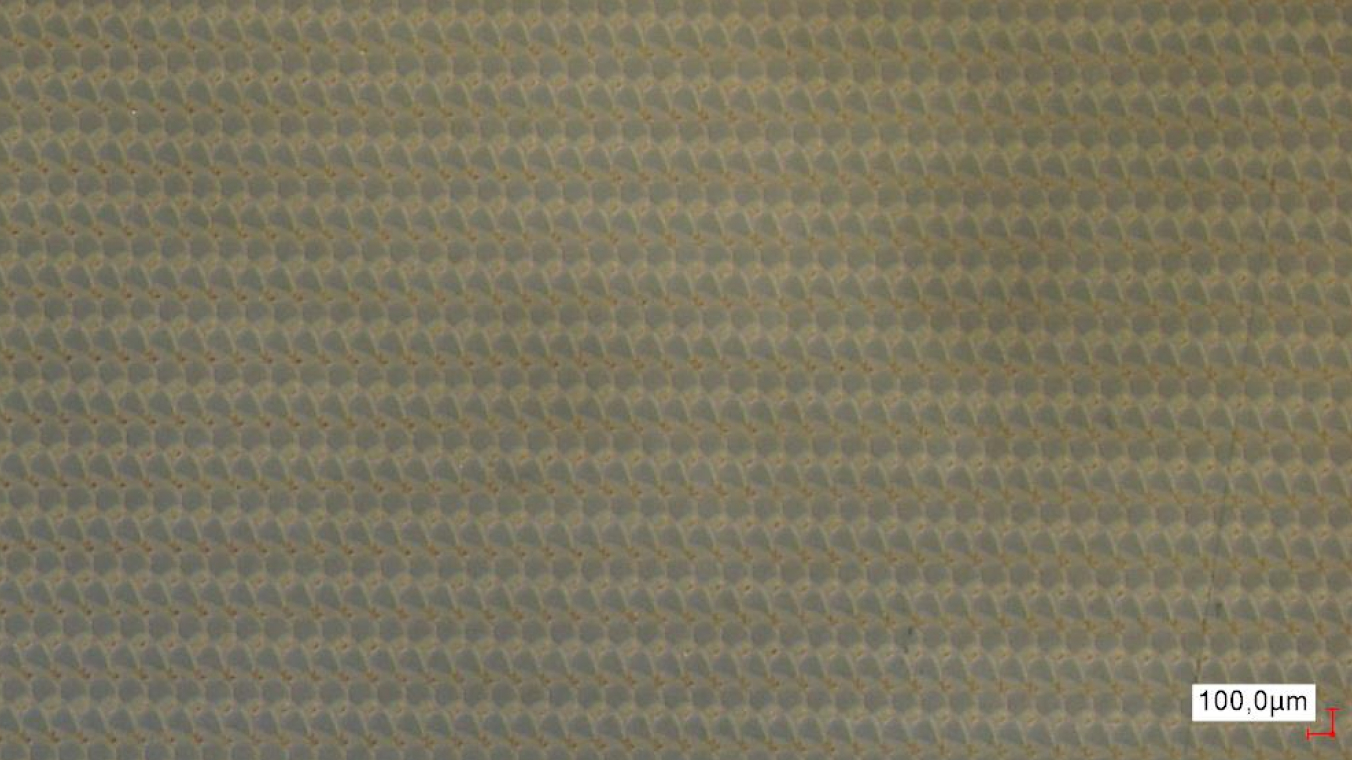 Mikroskopaufnahme eines regelmäßigen Abtragmusters. Die sich überlappenden Pulse sind einzelnd erkennbar.