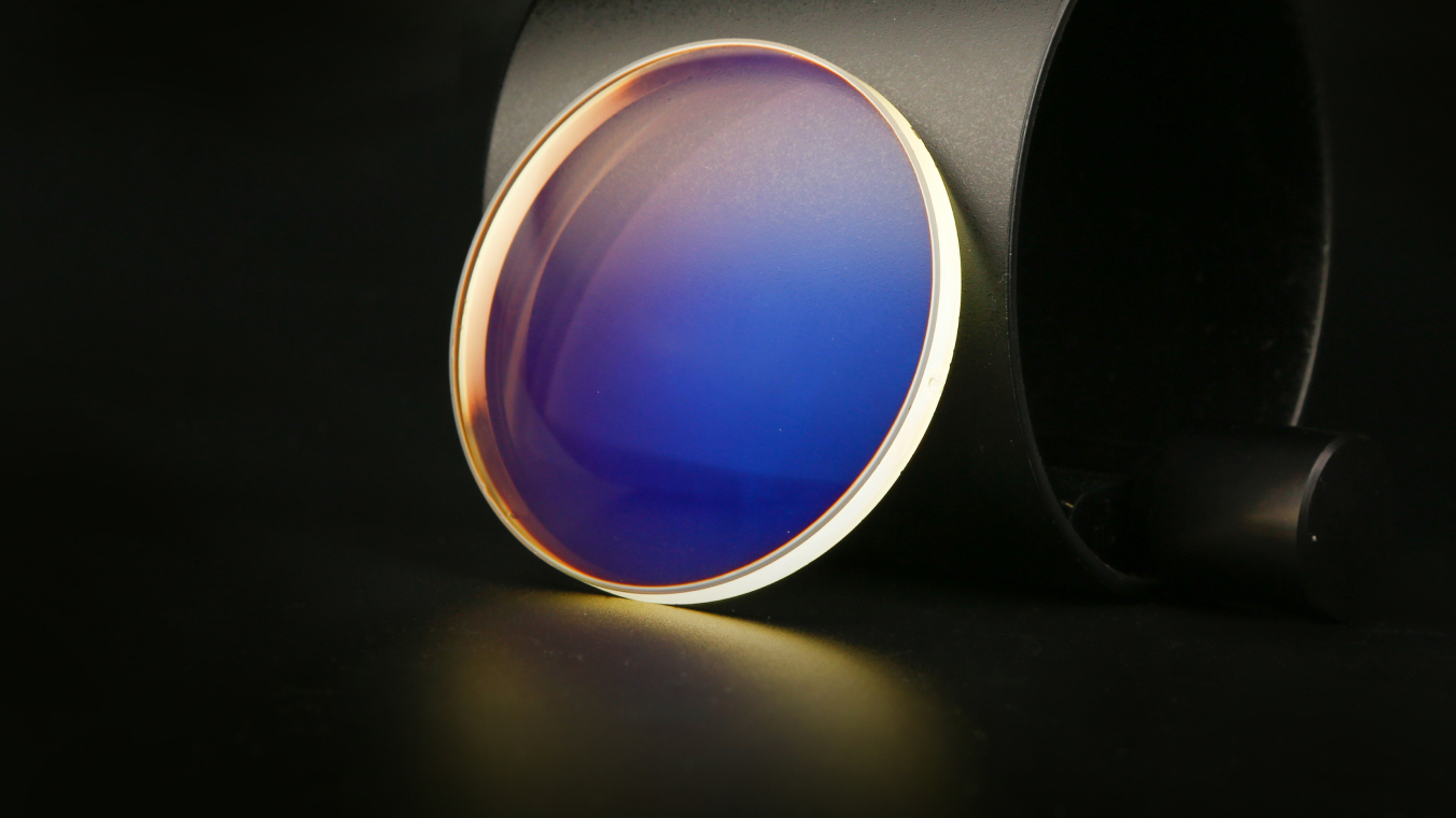 Nahaufnahme einer Glaslinse. Die Linse ist vor einem dunklen Hintergrund hell erleuchtet.