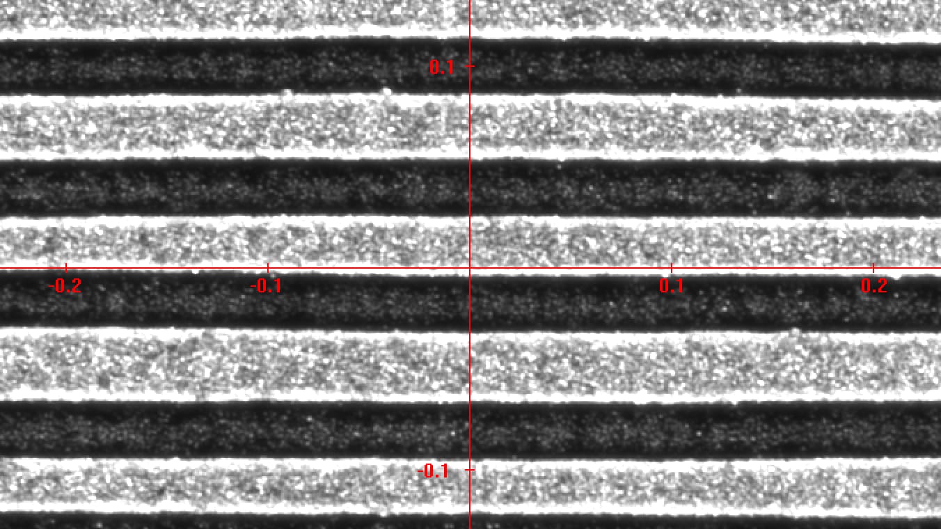 Mikroskopaufnahme einer linienförmigen Abtragsstruktur. Die Aufnahme zeigt abwechselnde dunkle und helle horizontale Linien